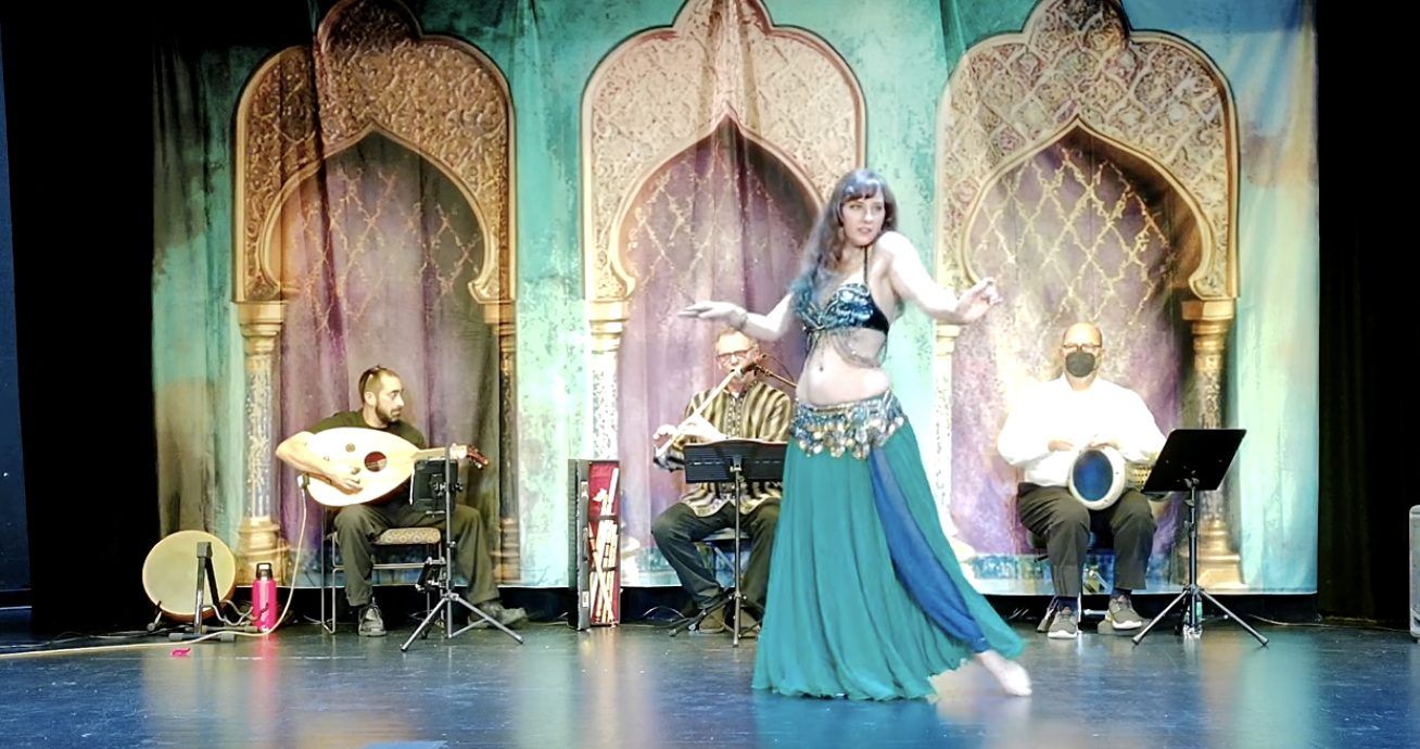 Amalphia Sylva dancing on stage with oud, flute and drum musicians